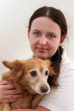 Žena drží malého štěněte v náručí.